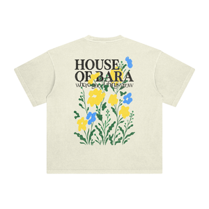 An off-white short-sleeve t-shirt with a graphic on the back featuring the text 'HOUSE OF BARA where good things grow' in black, overlaid with yellow and blue flowers and green leaves.